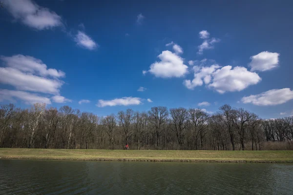 Ciclista a cavallo su una pista ciclabile lungo il fiume — Foto Stock