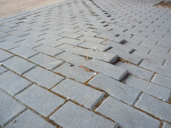 Gebroken betonnen pad baksteen oppervlak achtergrond, close-up abstracte gebarsten cement blok textuur Stockafbeelding
