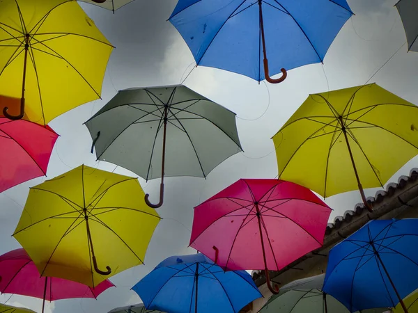 Színes esernyők lógnak a kék ég fölött. — Stock Fotó