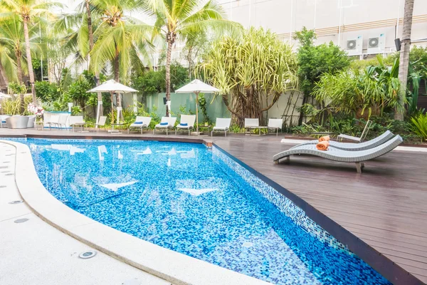 Paraguas y silla alrededor de una hermosa piscina de lujo — Foto de Stock