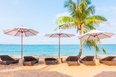 Şemsiyeleri ve sandalyeler tropik sahilde