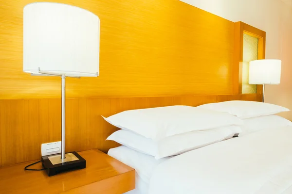 Almofadas brancas na cama com lâmpada de luz — Fotografia de Stock