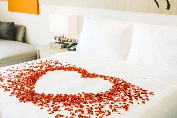 Білі подушки на ліжку і пелюстки троянд — стокове фото