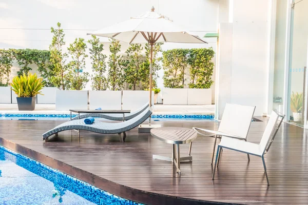 Guarda-chuva e cadeira em torno da bela piscina de luxo — Fotografia de Stock