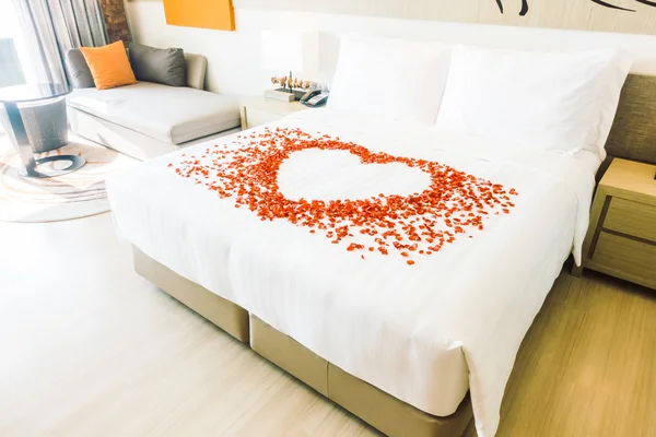 Белые подушки на кровати и лепестки роз — стоковое фото