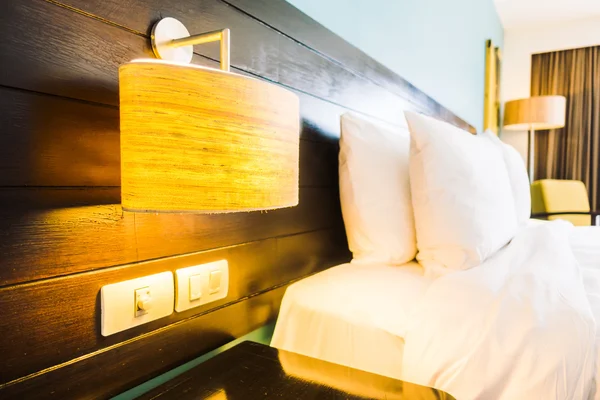 Almohadas en la cama y lámpara de luz en la pared — Foto de Stock