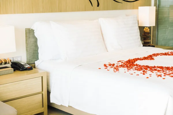 Білі подушки на ліжку і пелюстки троянд — стокове фото