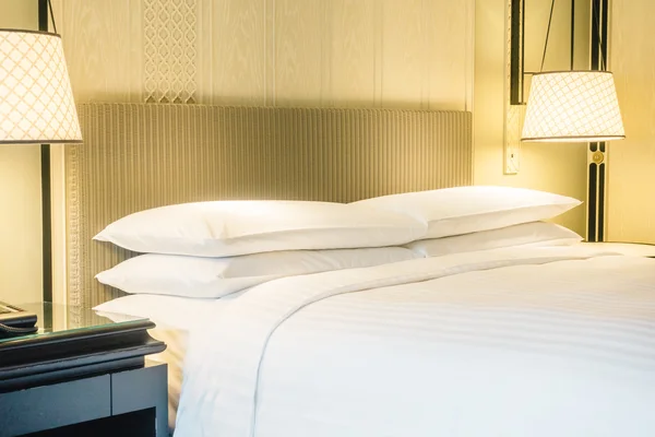 Белые подушки на кровати и легкая лампа — стоковое фото