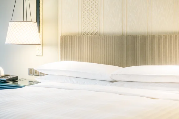 Travesseiros brancos na cama e lâmpada de luz — Fotografia de Stock
