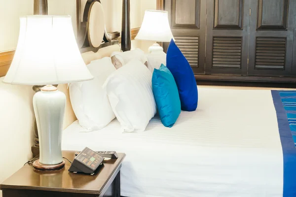 Роскошные подушки на кровати со светлой лампой — стоковое фото