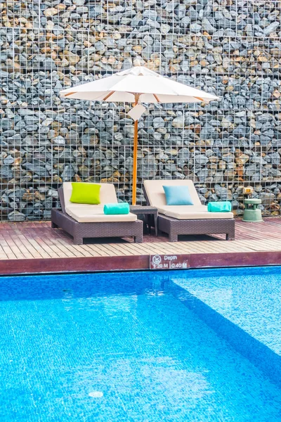 Guarda-chuva e cadeira em torno da piscina — Fotografia de Stock