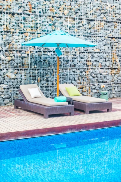 Guarda-chuva e cadeira em torno da piscina — Fotografia de Stock