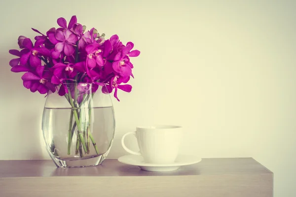 Taza de café con jarrón de flores de orquídea — Foto de Stock