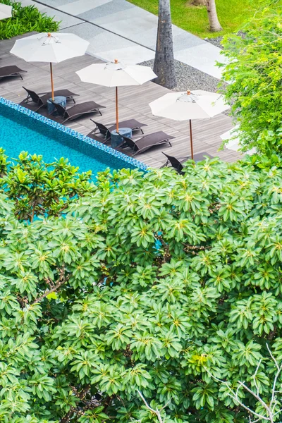 Paraguas y silla alrededor de la piscina — Foto de Stock