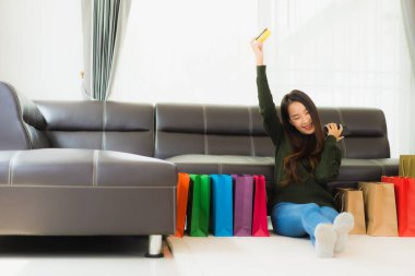 Alışveriş çantası ve kredi kartıyla evden online alışveriş için cep telefonlu güzel Asyalı kadın portresi.