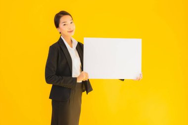 Güzel bir portre. Genç Asyalı kadın, sarı izole edilmiş arka planda boş beyaz tahta gösteriyor.