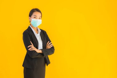 Güzel genç iş kadını portresi Korunmak için maske takıyor 19 koronavirüs sarı izole arka planda