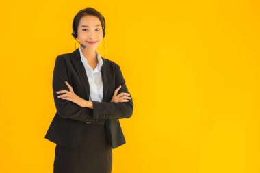 Portre güzel genç Asyalı kadın kulaklık ya da çağrı merkezi için kulaklık ya da tele pazarlama sarı izole arka planda.