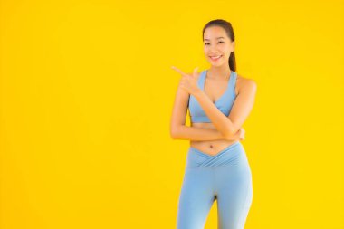 Sarı izole edilmiş arka planda spor giysili güzel Asyalı kadın portresi egzersize hazır.
