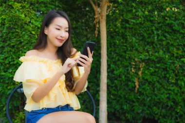 Genç Asyalı kadın açık hava manzarası için akıllı cep telefonu kullanıyor.