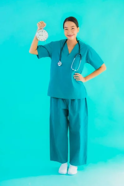 ポルトガルの美しい若いアジアの医師の女性ショークロックまたはアラーム上の青隔離された背景 — ストック写真