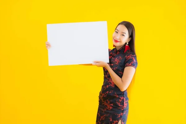 穿着中国服装的美丽的亚洲年轻女子形象在中国新年的概念中 在黄色孤立的背景下 展示了白纸空白字的广告牌 — 图库照片