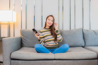 Güzel bir Asyalı kadın. Oturma odasındaki kanepede müzik dinliyor.