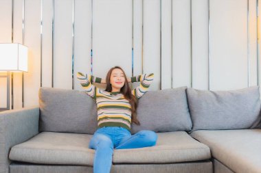 Portre güzel Asyalı kadın gülümsemesi. Oturma odasındaki kanepede rahatla.