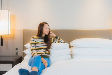 Güzel bir Asyalı kadın portresi. Mutlu bir gülümseme. Yatak odasında iç tarafta rahatla.