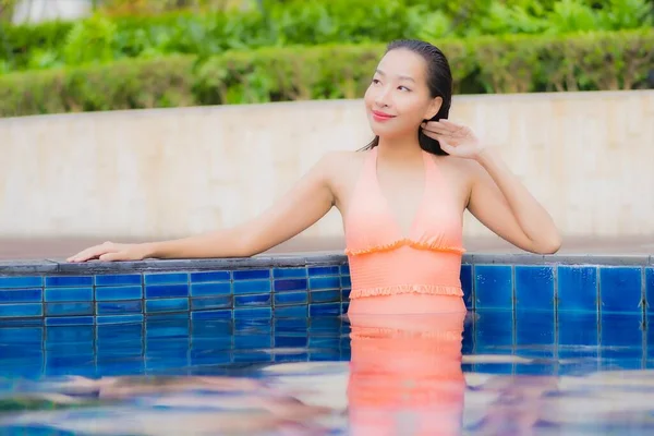美しい若いアジアの女性がホテルのリゾートで屋外スイミングプールの周りで笑顔をリラックス — ストック写真
