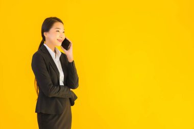 Portre güzel genç Asyalı kadın akıllı cep telefonu ve kahve fincanı ile izole edilmiş sarı arka planda