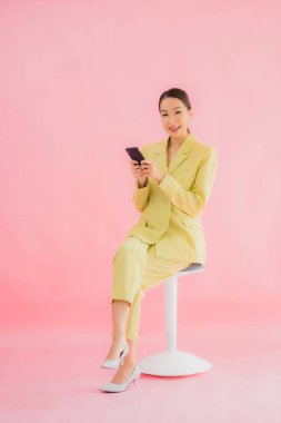 Güzel Asyalı iş kadını portresi. Arka planda kahve fincanı ve akıllı cep telefonu kullanıyor.