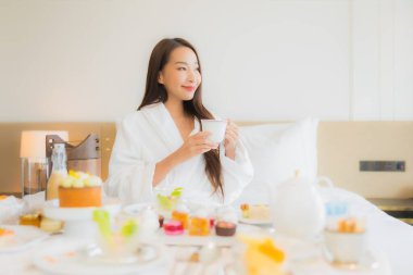 Güzel bir Asyalı kadının portresi. Yatak odasındaki iç kısımda kahvaltıda iyi eğlenceler.