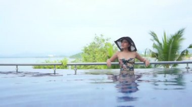 Güzel, genç Asyalı kadın rahatla. Yüzme havuzunda gülümse. Otel odasında.