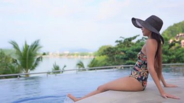 Güzel, genç Asyalı kadın rahatla. Yüzme havuzunda gülümse. Otel odasında.