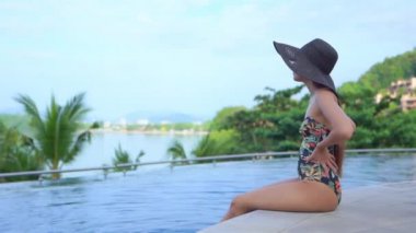 Güzel, genç Asyalı bir kadın oteldeki yüzme havuzunda dinleniyor.