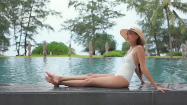 美しい若いアジア人女性がホテルリゾートの屋外スイミングプールでリラックス — ストック動画