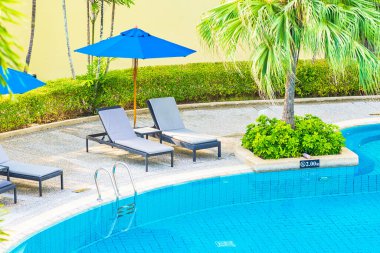 Güzel boş sandalye ve şemsiyeli açık havuz oteldeki tatil gezisi için.