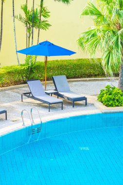 Güzel boş sandalye ve şemsiyeli açık havuz oteldeki tatil gezisi için.