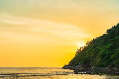 Sahildeki okyanusun etrafındaki dağda güzel bir gün batımı ve doğa gezisi için kaya.