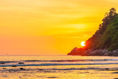 Sahildeki okyanusun etrafındaki dağda güzel bir gün batımı ve doğa gezisi için kaya.