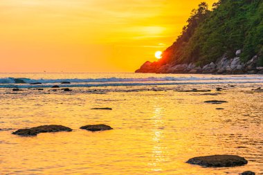 Sahildeki okyanusun etrafındaki dağda güzel bir gün batımı ve doğa gezisi için kaya.
