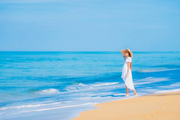 Portrait beautiful young asian woman relax smile leisure around sea beach ocean with white cloud on blue sky in travel vacation