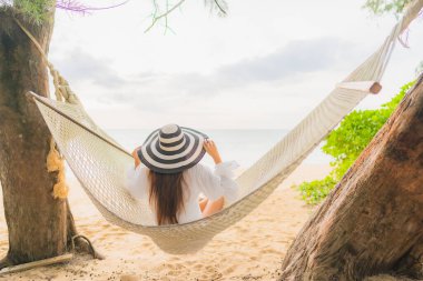 Güzel bir Asyalı kadın portresi deniz kıyısındaki hamakta dinleniyor.