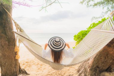 Güzel bir Asyalı kadın portresi deniz kıyısındaki hamakta dinleniyor.