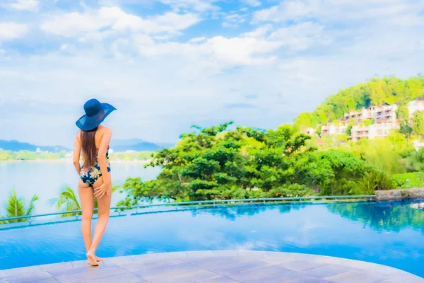 亚洲年轻貌美的女子在户外游泳池边游玩 一边欣赏大海的美景 一边放肆地微笑 — 图库照片