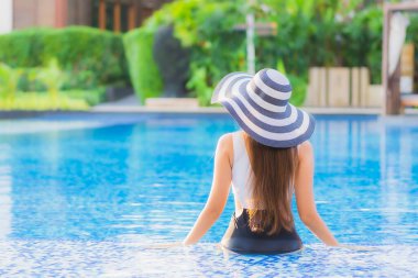 Güzel bir portre genç Asyalı mutlu bir gülümseme tatil beldesi otelinde havuzda rahatça yüzebiliyor.