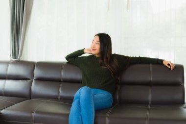 Güzel bir portre. Genç Asyalı kadın. Oturma odasındaki kanepede rahatla.