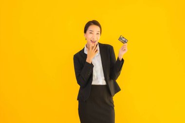 Sarı izole edilmiş arka planda kredi kartı olan güzel, genç Asyalı kadın portresi.