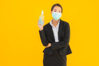 Güzel bir iş kadını portresi. Maske takıyor. Korunmak için alkol jeli kullanıyor.